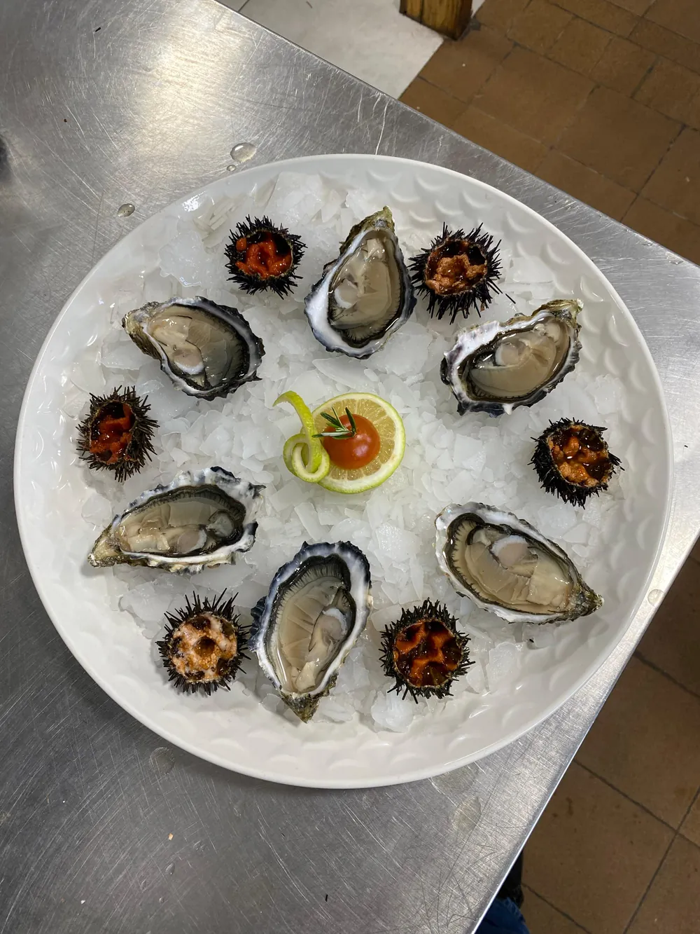 Assiette d'huîtres creuses et d'oursins ouverts sur glace pilée, sauce cocktail et citron au centre