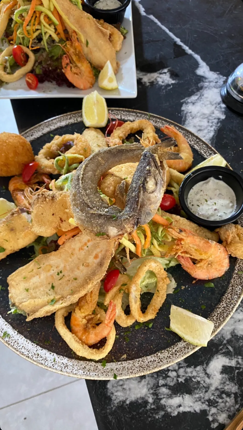 Grande assiette de friture : poisson entier, filets, calamars, crevettes, croquette et sauce blanche, salade en arrière-plan